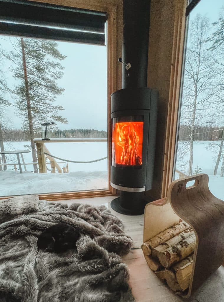 Musta takka loimuaa Ehta-rakennuksen ikkunan vieressä, taustalla luminen järvimaisema