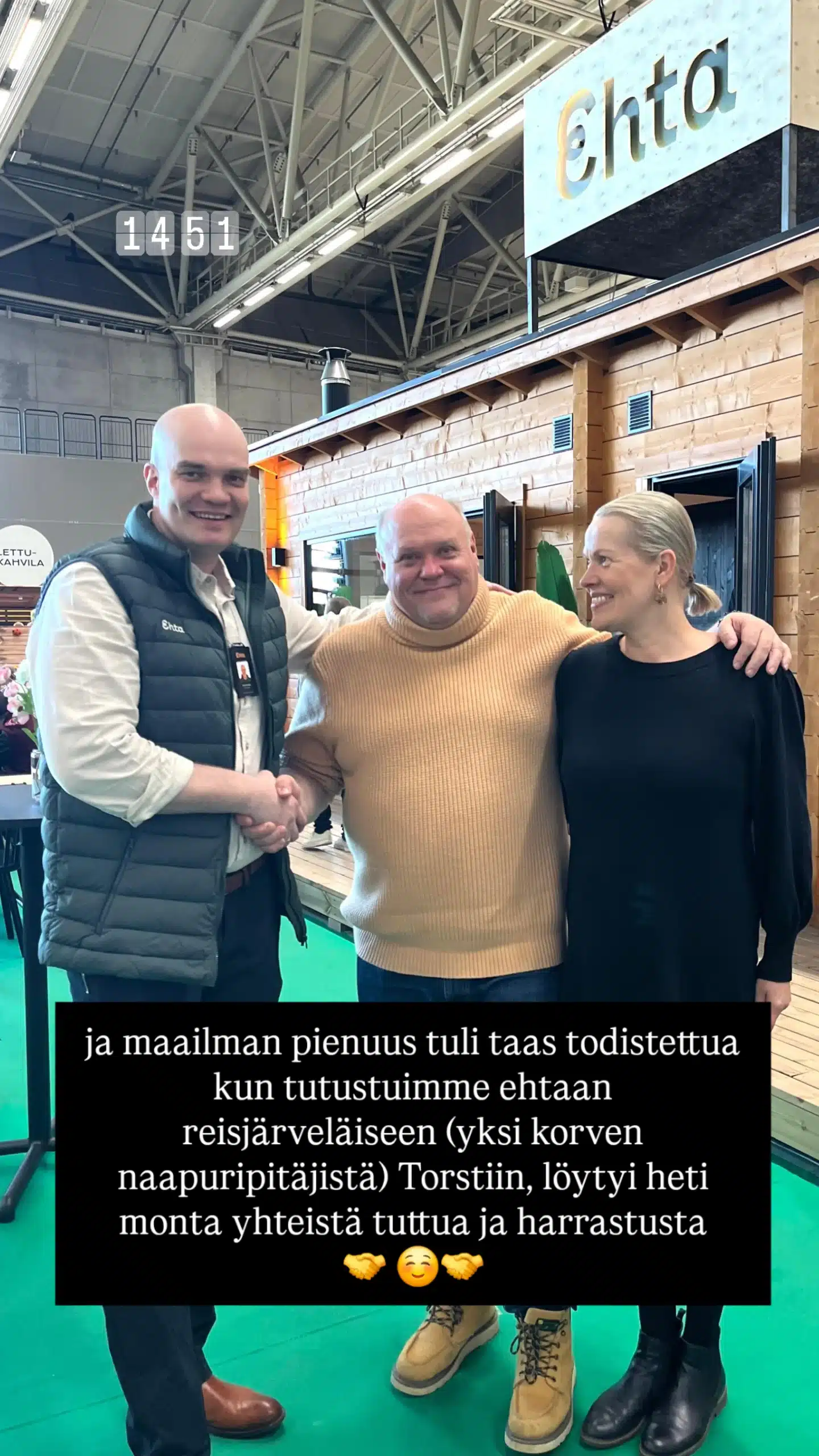 Sisätiloissa seisoo kolme henkilöä, joista kaksi kättelee ja hymyilee. Taustalla näkyy puinen koju, jossa lukee ”Ehta”. Kuvan poikki on kirjoitettu suomeksi.