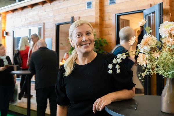 Kirsi Alm-Siira hymyilee tyylikkäässä, tummassa asussa Ehta -messumökin edustalla. Kirsi antoi vinkkejä saunamökin suunnitteluun ja hankintaan Kevätmessuilla 2025
